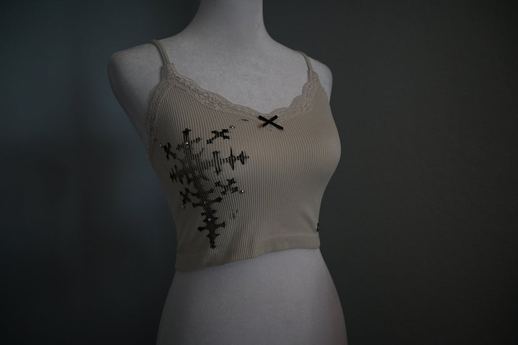 Beige tank top with black cross design on a mannequin against a dark background