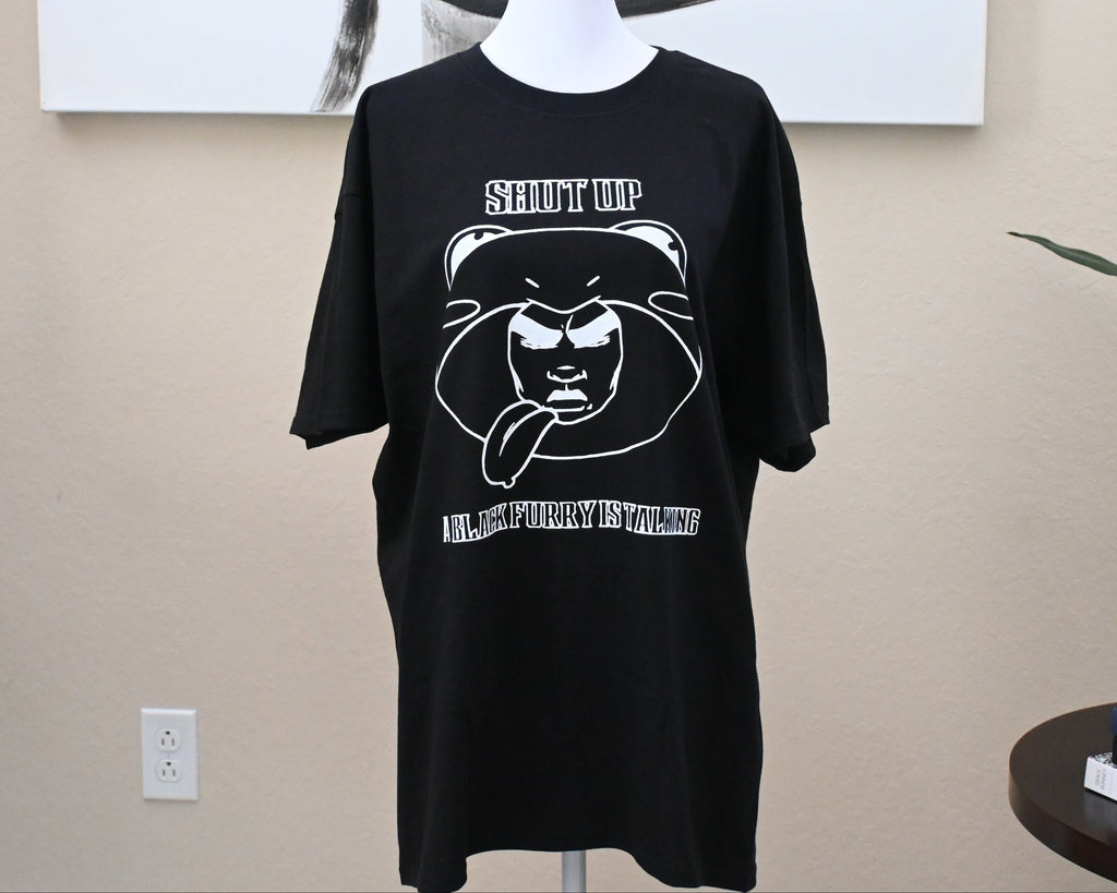 Black t-shirt with graphic design on a mannequin against a beige wall.