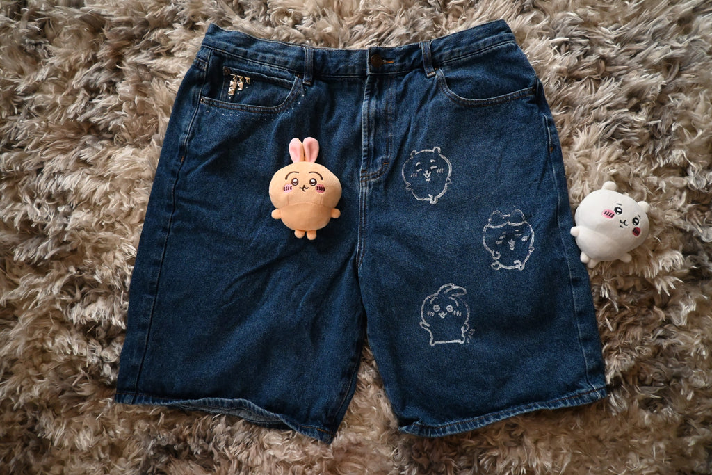 Blue denim shorts with chiikawa designs on a textured brown surface