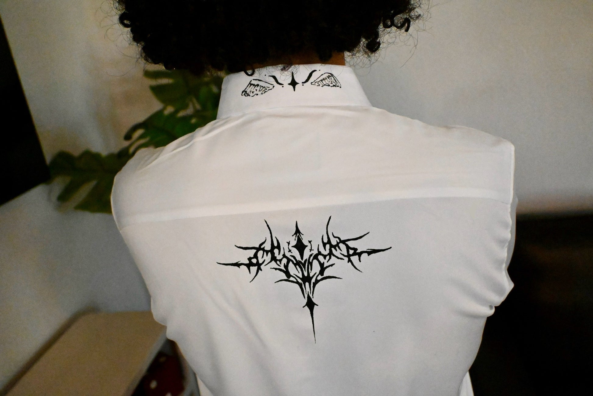 A white button up with stars on the collar and front, as well as a cybersigilism design on the back.