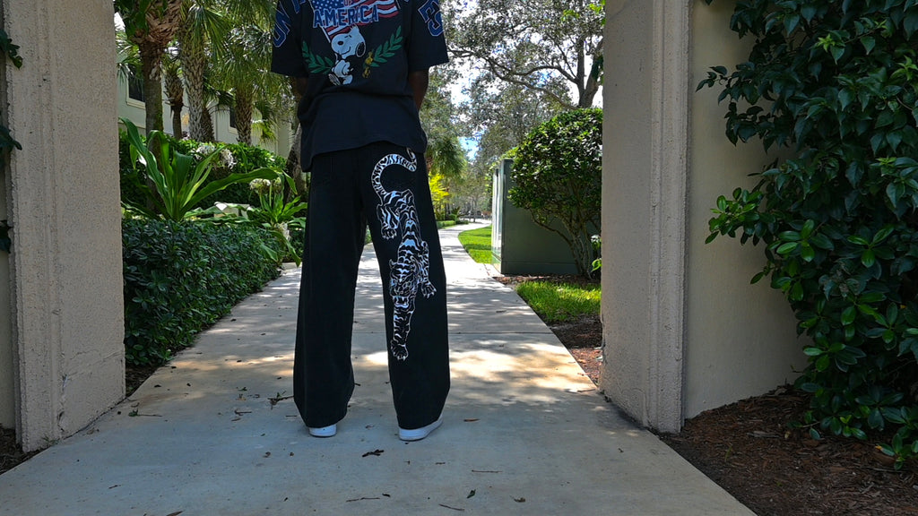 A black pair of jeans with a white tiger painted on.
