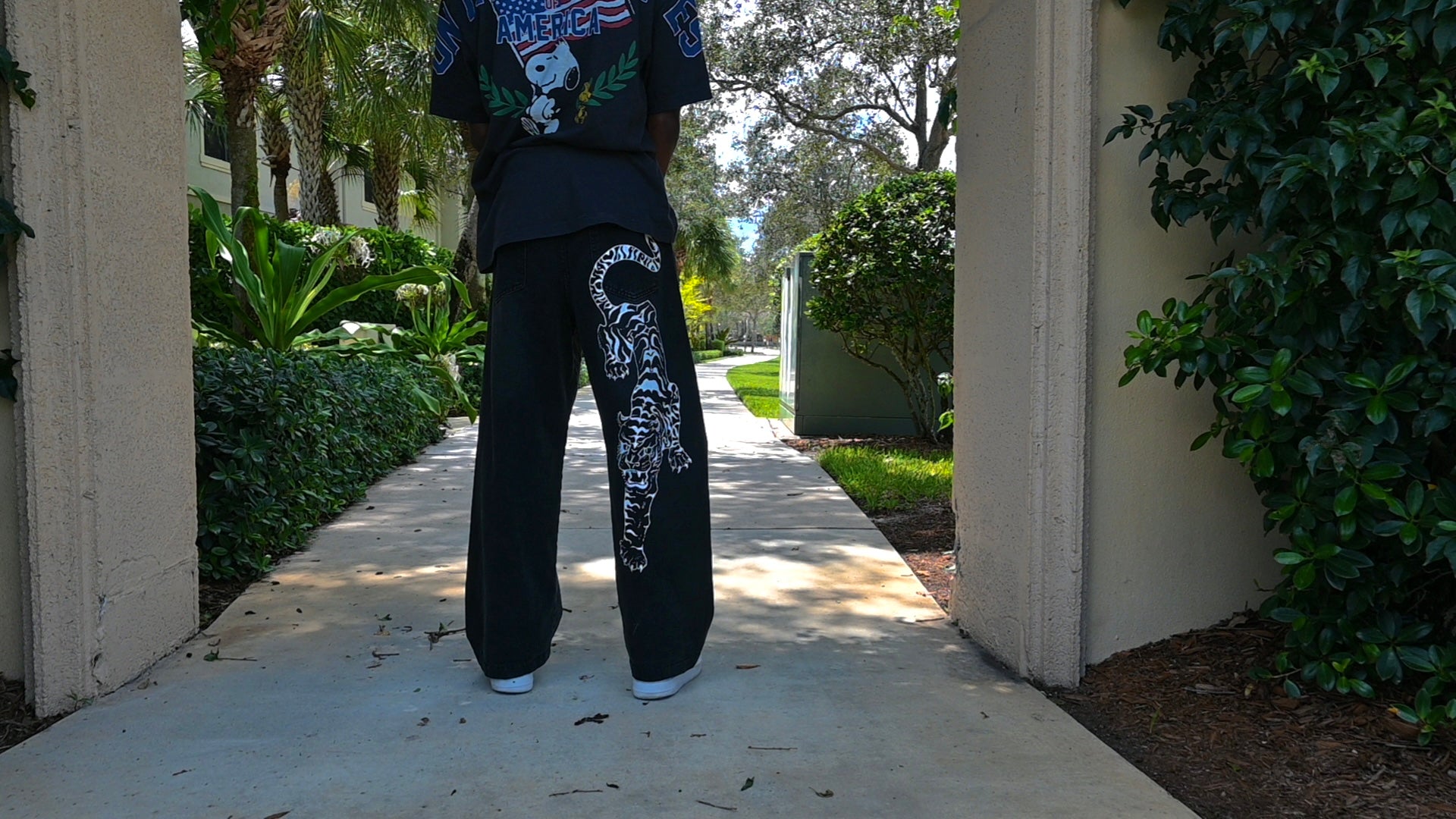 A black pair of jeans with a white tiger painted on.