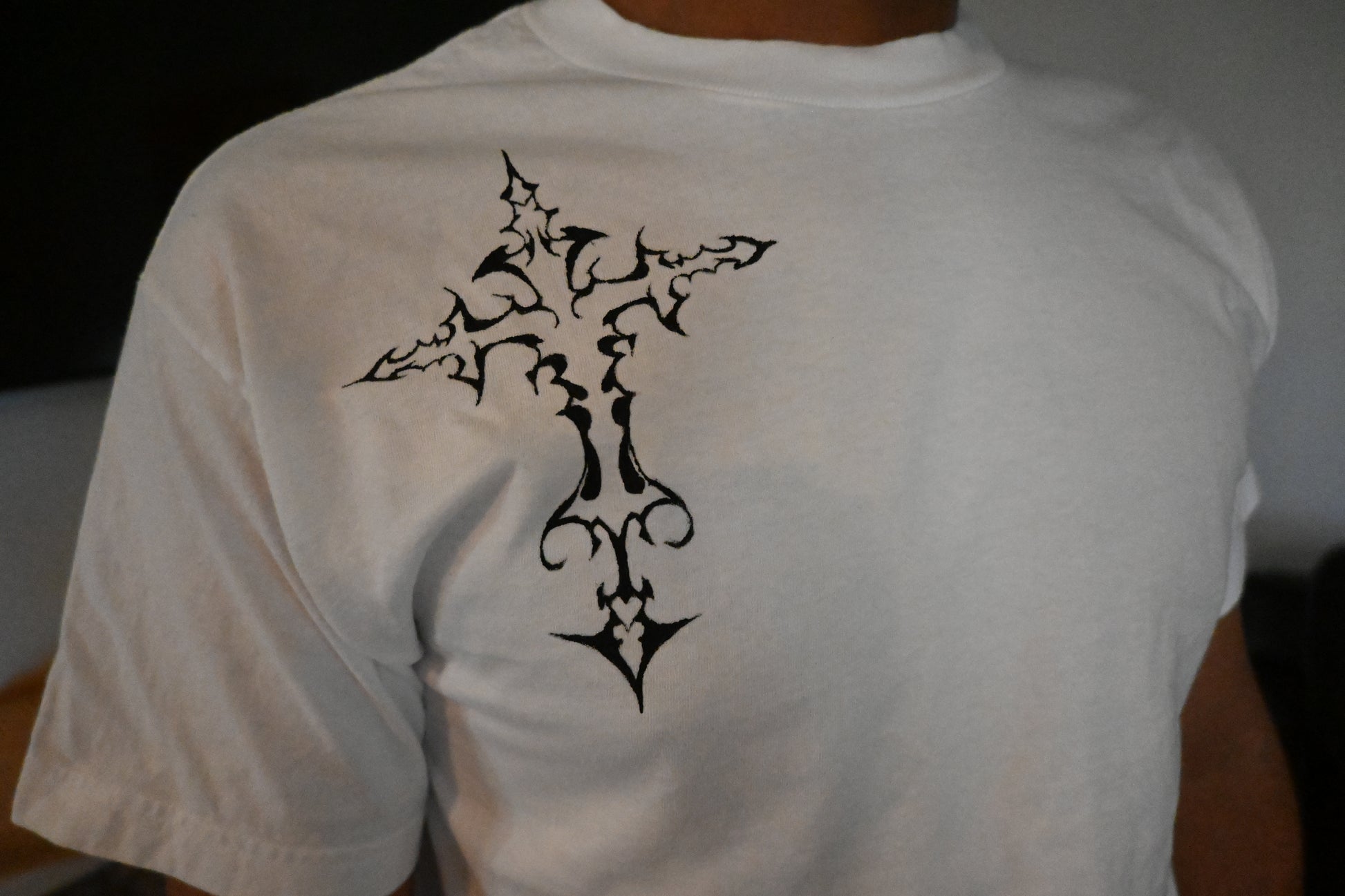 A hand painted white t-shirt with a black cross design.