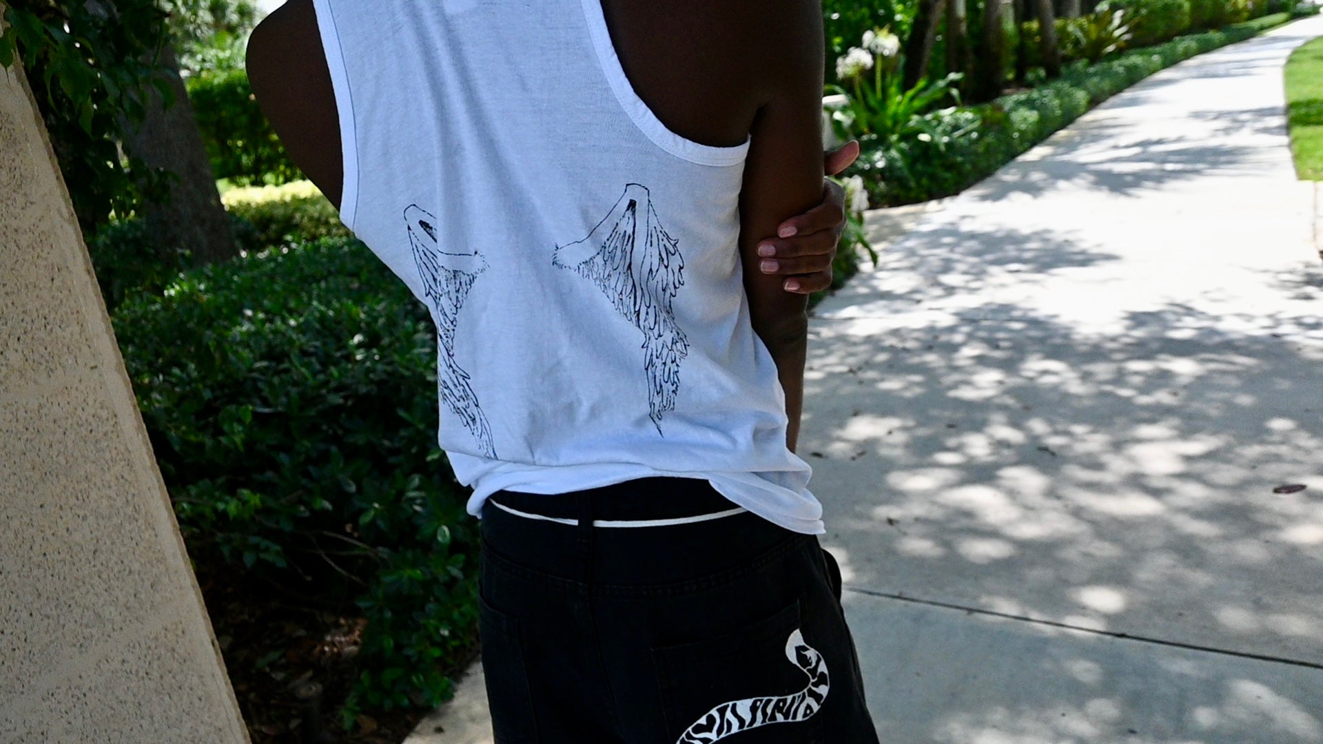 A hand painted wife beater with a cross design on the front and wings on the back.