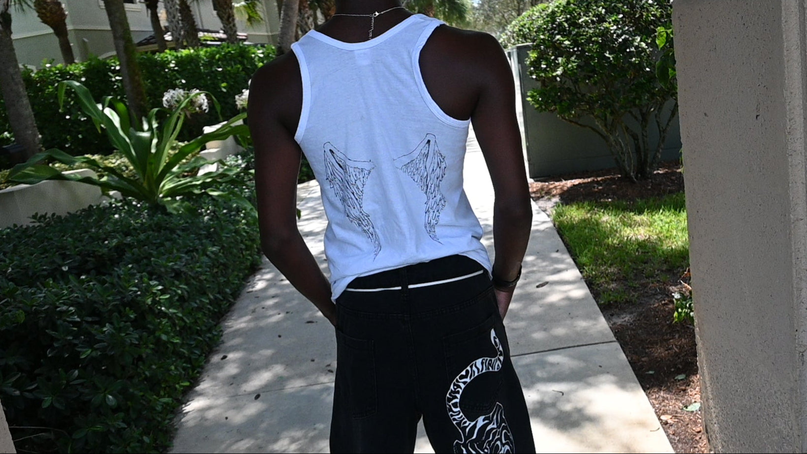 A hand painted wife beater with a cross design on the front and wings on the back.