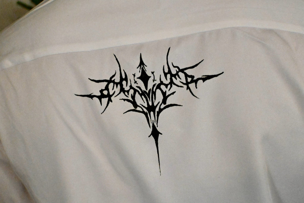 A white button up with stars on the collar and front, as well as a cybersigilism design on the back.