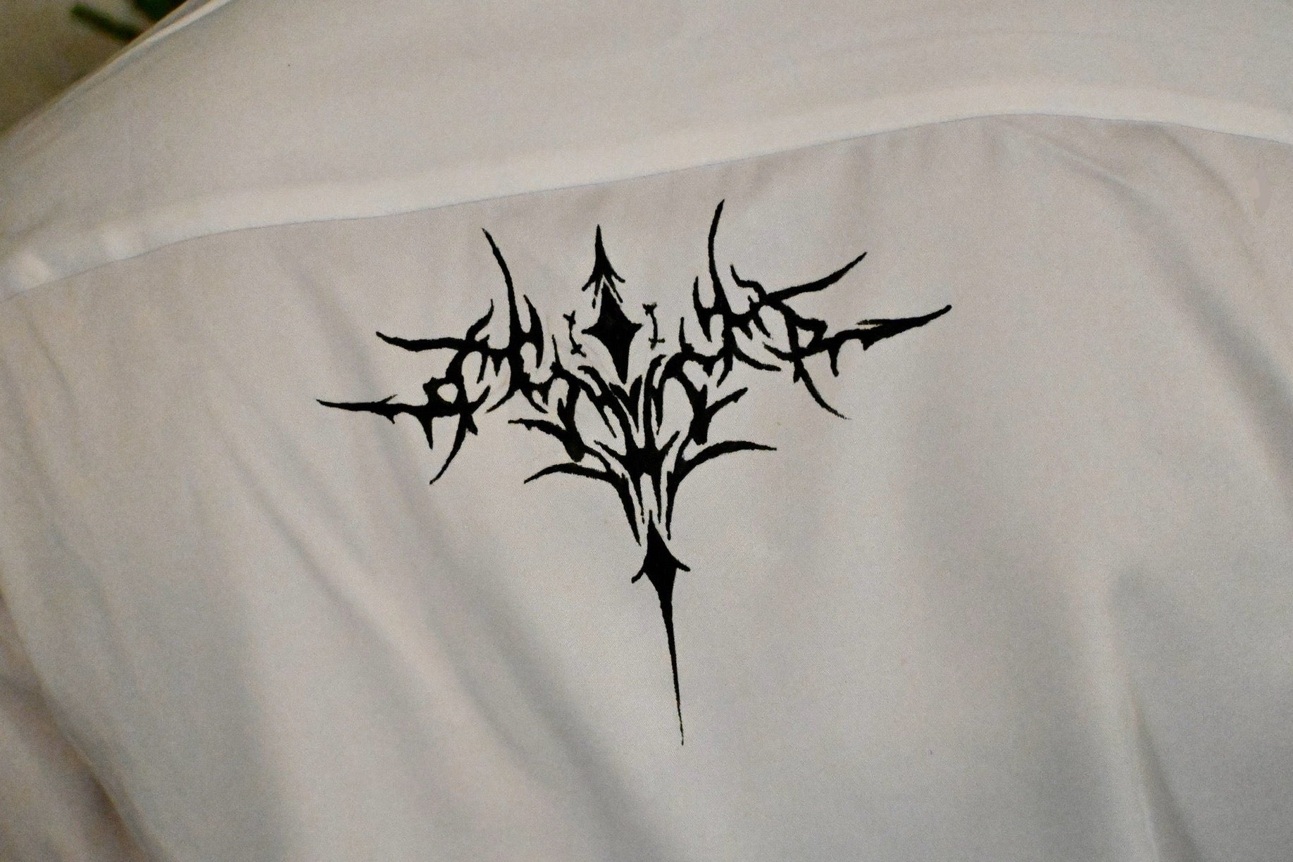 A white button up with stars on the collar and front, as well as a cybersigilism design on the back.