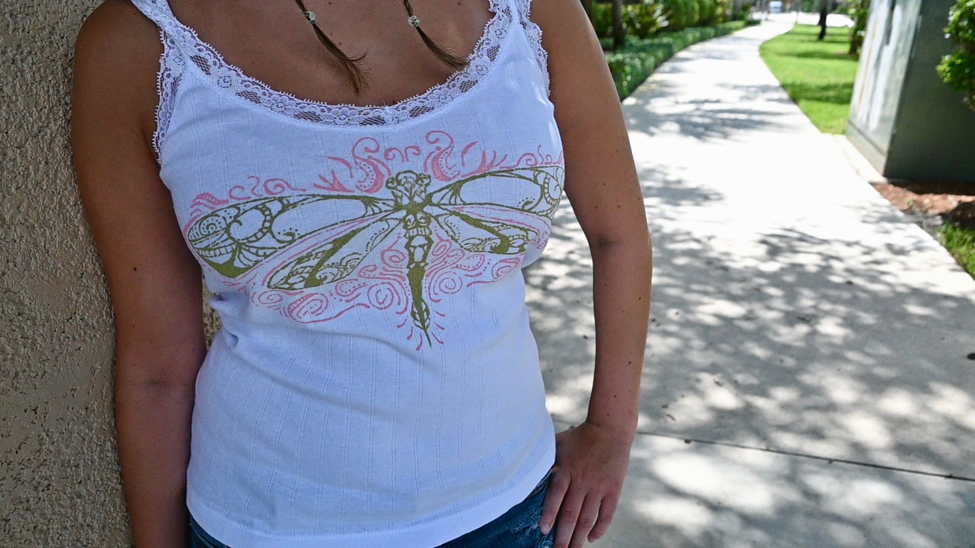 A hand painted lace tank top with a green dragonfly design and pink accents.