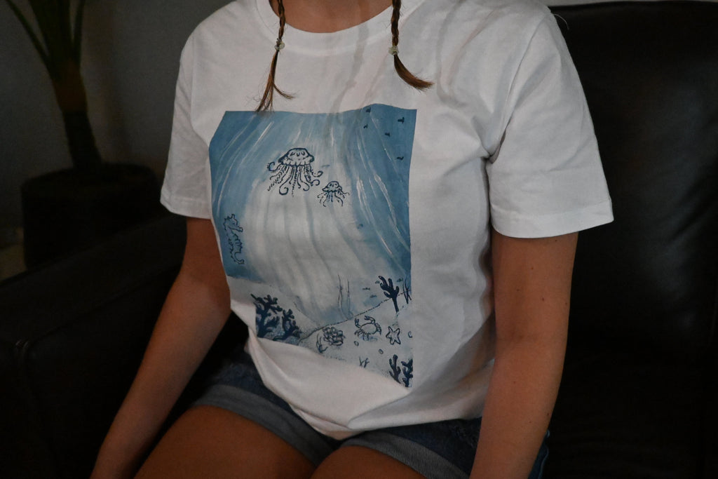 A hand painted white t-shirt with a blue ocean design across the front.