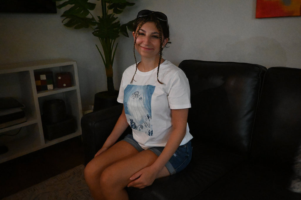A hand painted white t-shirt with a blue ocean design across the front.