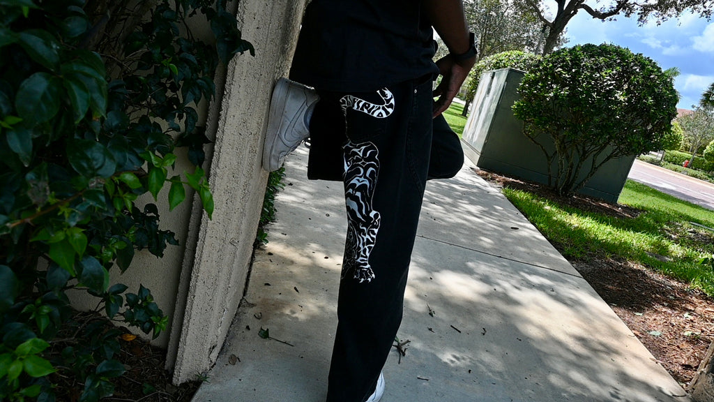 A black pair of jeans with a white tiger painted on.