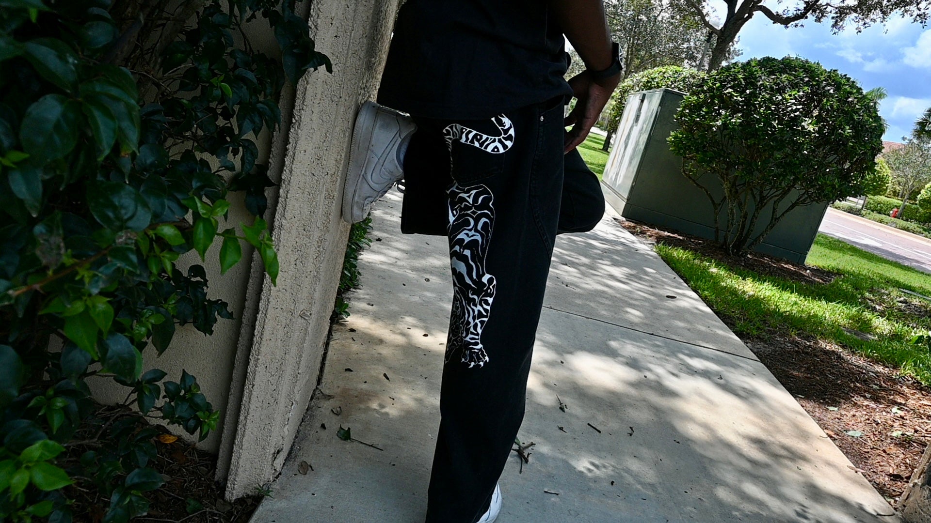 A black pair of jeans with a white tiger painted on.