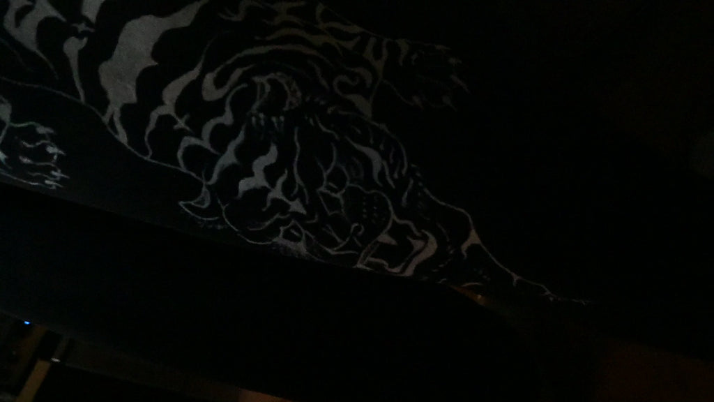 A black pair of jeans with a white tiger painted on.