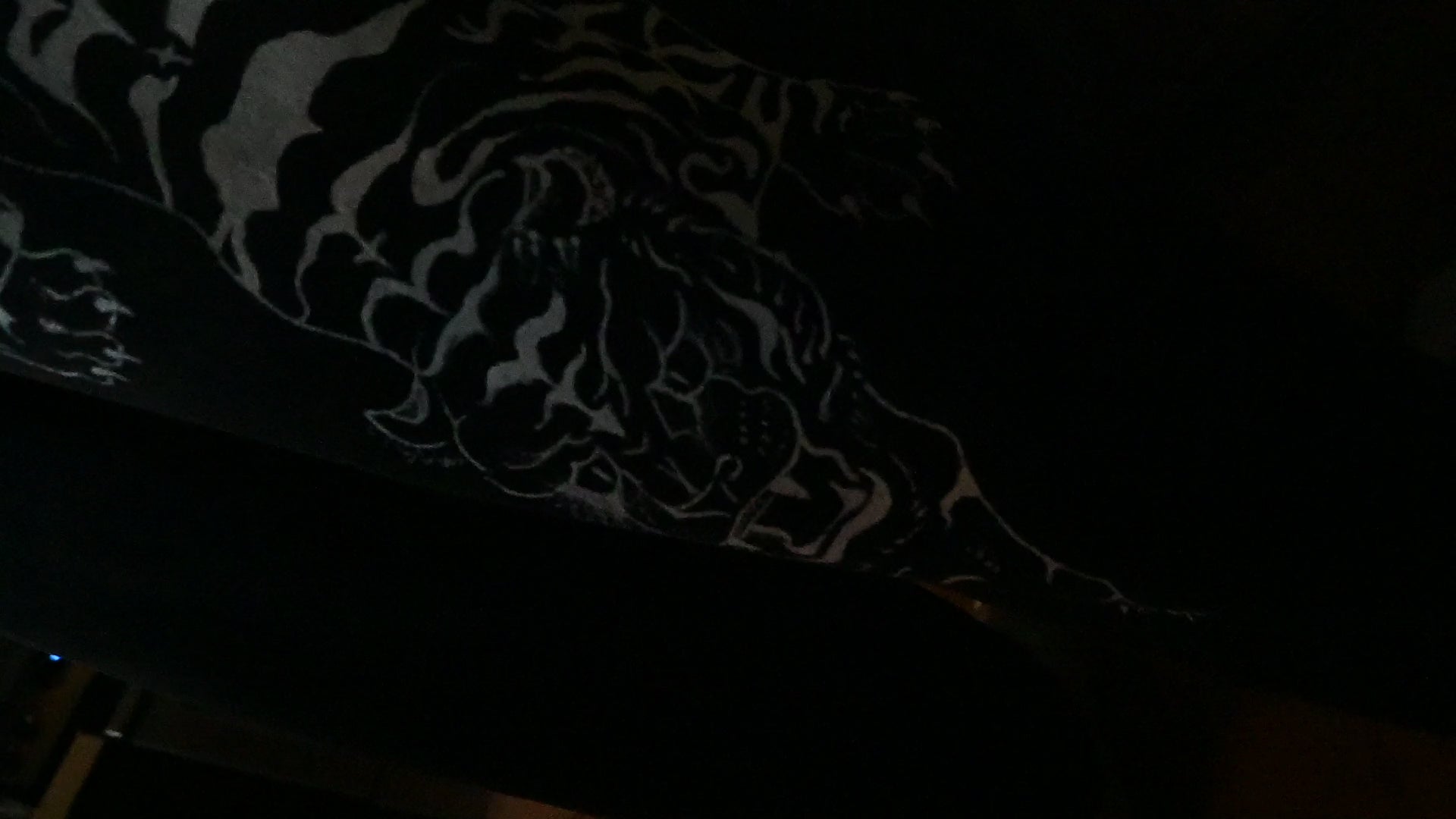 A black pair of jeans with a white tiger painted on.